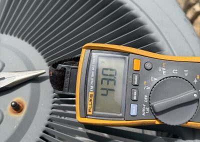 A Fluke multimeter resting on an AC unit grate, displaying a temperature reading of 43.0 degrees Fahrenheit.
