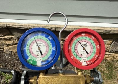 A blue low-pressure gauge and a red high-pressure gauge on an HVAC manifold set.