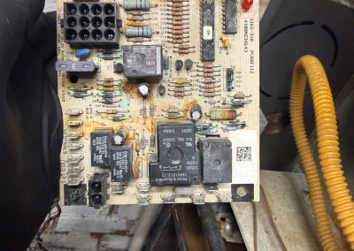 A rectangular HVAC control circuit board with visible corrosion and electronic components.