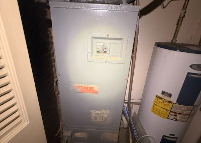 A gray York furnace unit next to a white water heater.