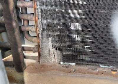 Damaged air conditioning condenser fins with signs of corrosion.