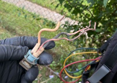 Technician holding a damaged HVAC wiring connector with frayed wires