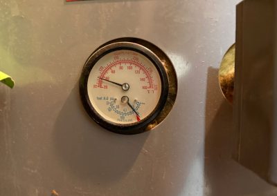 HVAC gauge showing temperature and pressure readings, with a Zoned Heating and Cooling business card above it.