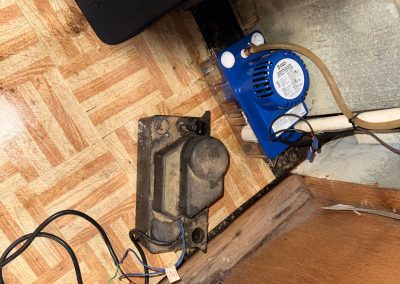 A blue condensate pump next to an old, disconnected pump motor on a tiled floor.