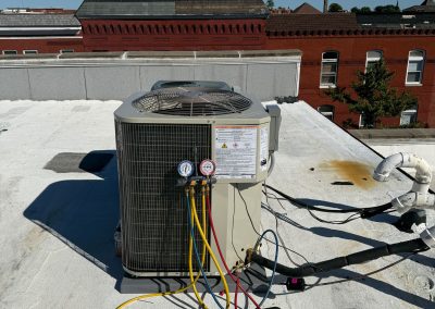 Rooftop air conditioning unit connected to manifold pressure gauges.